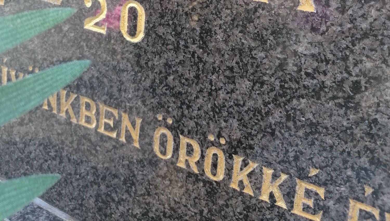 Aranyozott, kézzel vésett betűk részlete egy gránit sírkövön
