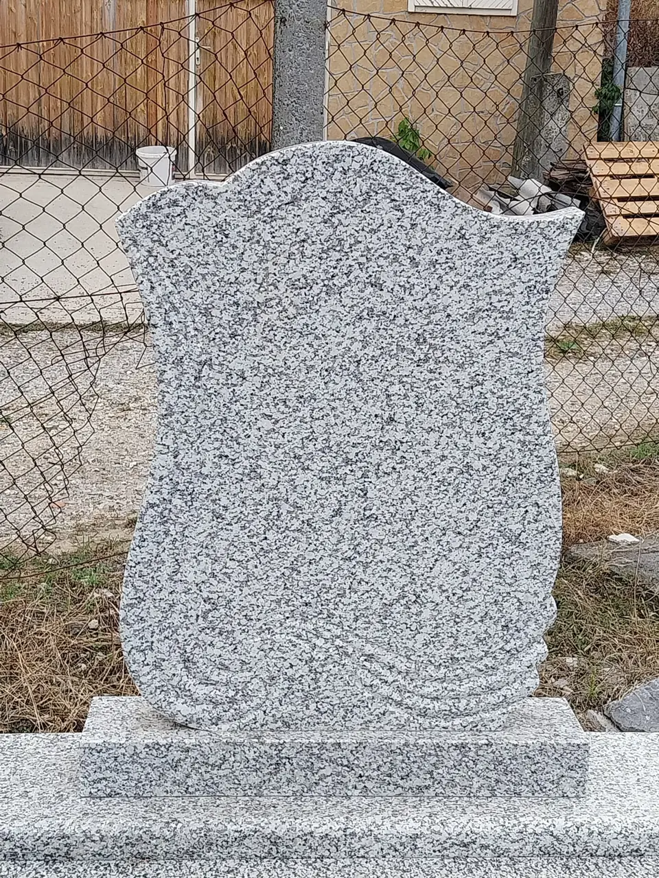 Világosszürke gránit fejkő talapzaton